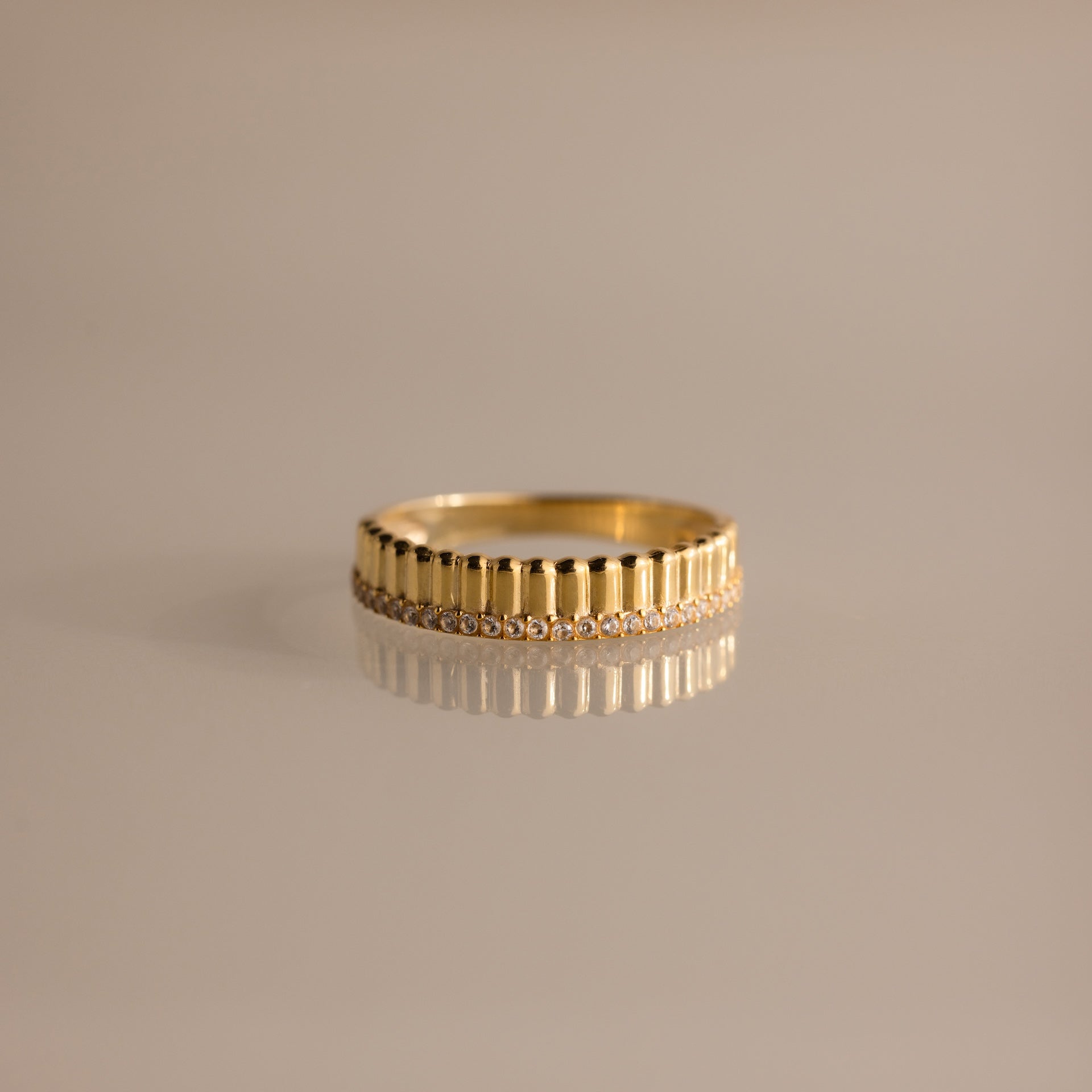 Ribbed Diamond Stack Ring featuring vertical ridges and a row of sparkling diamonds, displayed on a reflective surface.