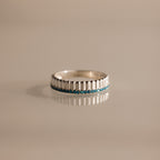 A Ribbed Blue Zircon Stack Ring, featuring a row of small blue zircon gemstones, is displayed on a neutral background.