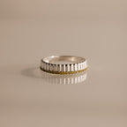 The Ribbed Peridot Stack Ring features a silver ribbed texture with vertical grooves and a row of small yellow peridot stones, shown on a neutral background. A modern, stackable ring perfect for versatile styling.