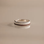 The Ribbed Garnet Stack Ring features a row of small red garnet stones set in silver, ideal for layering with other rings and shown on a beige surface.