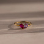 The Toi et Moi Teardrop Heart Ring in 18K Gold features two heart-shaped pink and purple gemstones set side by side in a romantic design.