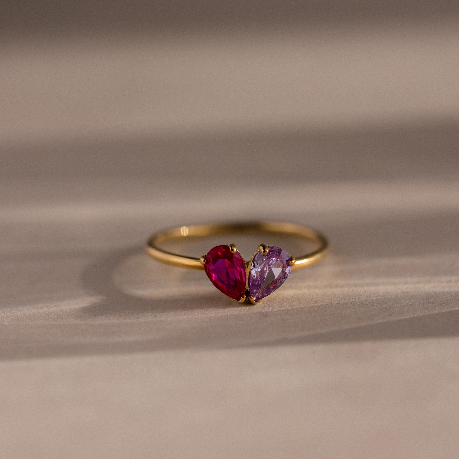 The Toi et Moi Teardrop Heart Ring in 18K Gold features two heart-shaped pink and purple gemstones set side by side in a romantic design.