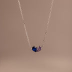 The Toi et Moi Teardrop Heart Necklace in Sterling Silver features two pear-cut stones—one blue, one purple—set on a plain background; a timeless keepsake ideal for any occasion.