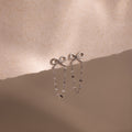 Bow Chain Studs in Sterling Silver with a delicate beaded chain drop, displayed on soft beige fabric. A charming piece for any vintage-inspired jewelry collection.