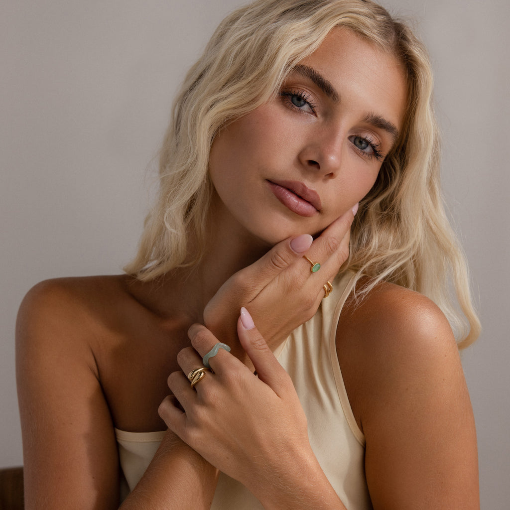 Model wearing the Jade Wave Ring, styled with multiple gold and green jade rings.