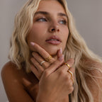 A model wearing the Diamond Cluster Curve Ring alongside other golden rings for a stacked, layered look