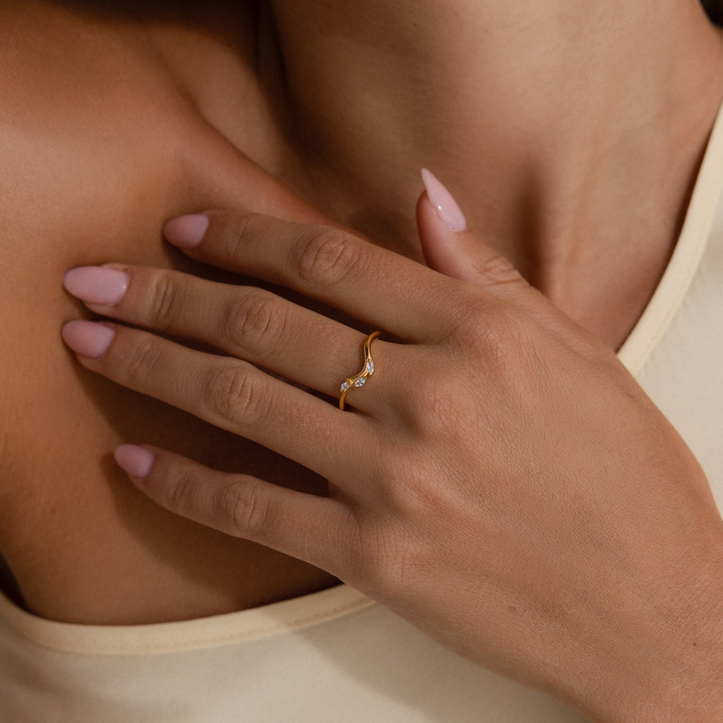 Model wearing a gold curve marquise diamond ring with three marquise cut diamonds.
