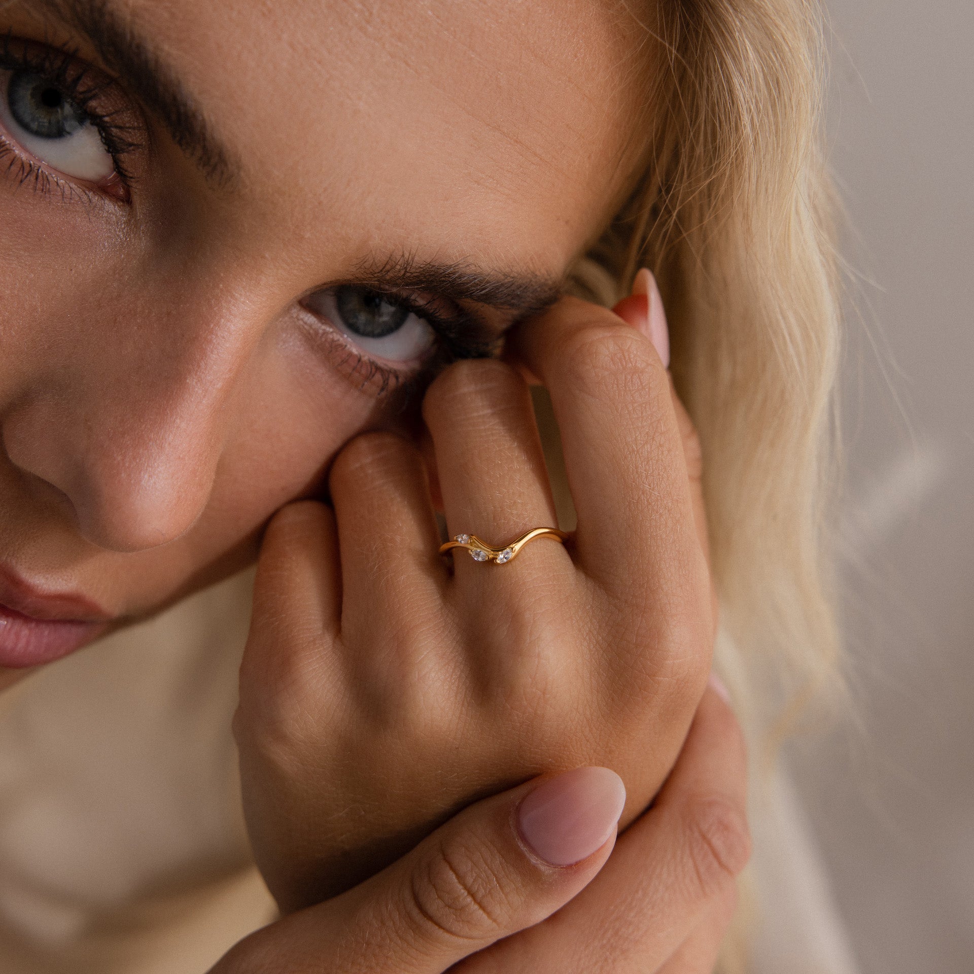 Close-up of model wearing a gold curve marquise diamond ring with three marquise cut diamonds.