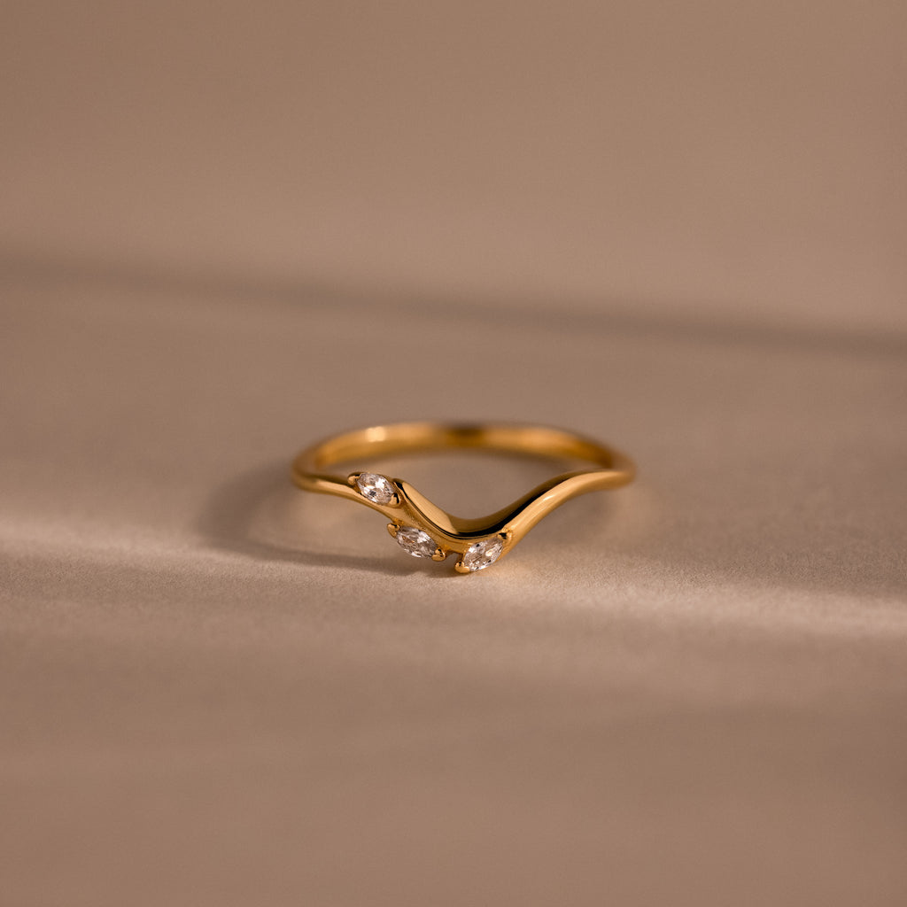 Gold curve marquise diamond ring with three sparkling marquise-cut diamonds in a chevron setting.