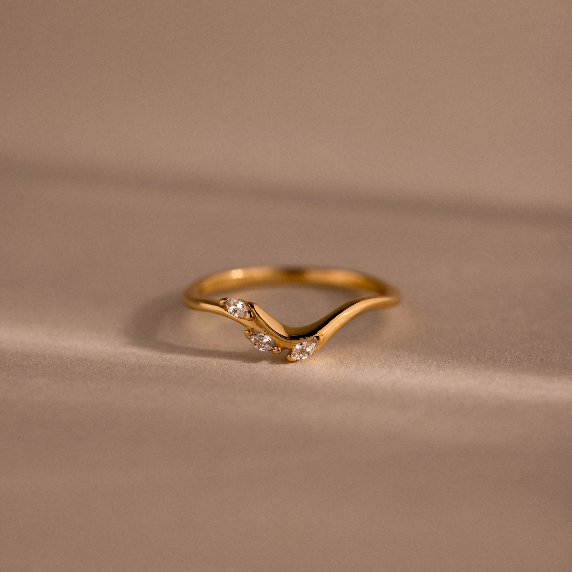 Gold curve marquise diamond ring with three sparkling marquise-cut diamonds in a chevron setting.