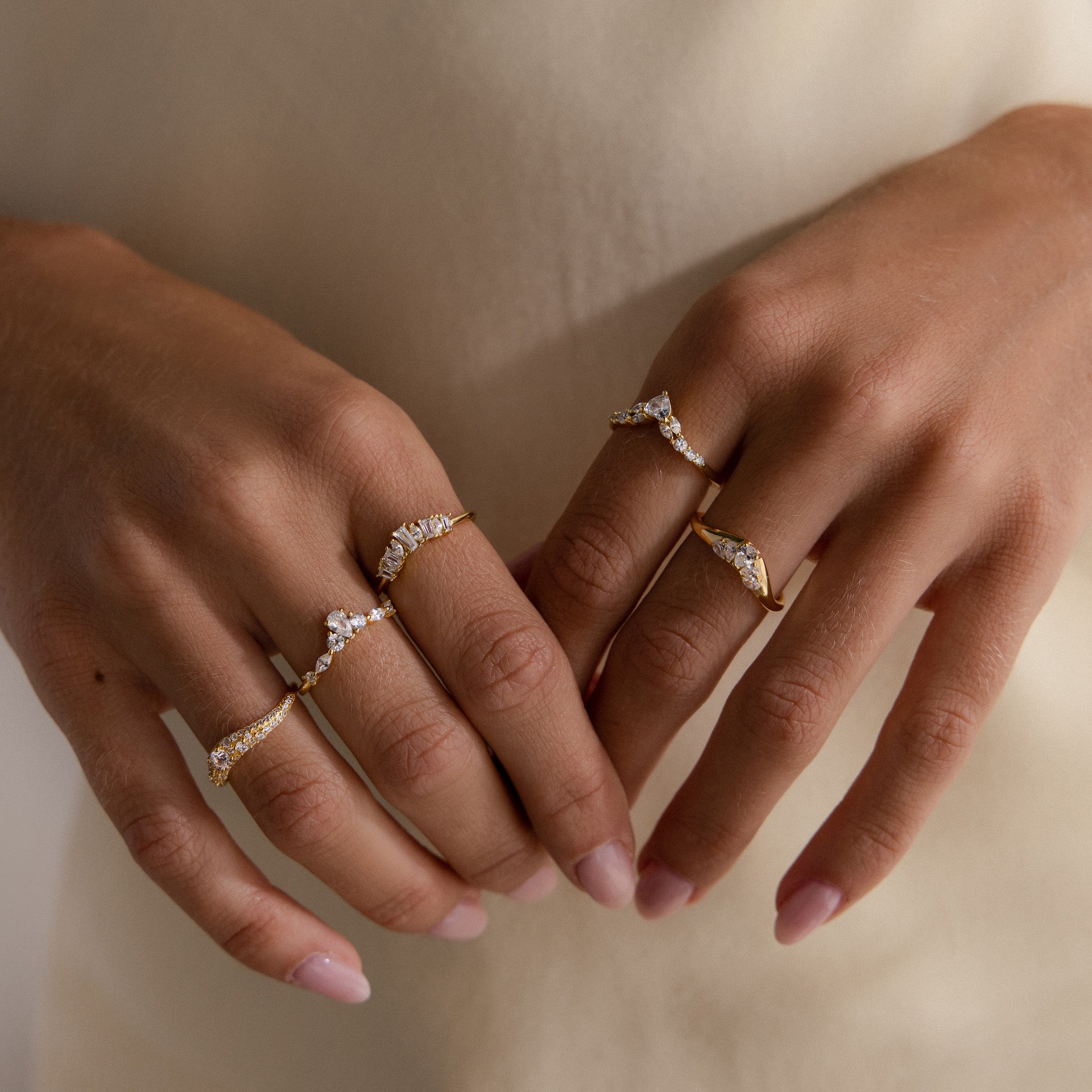 Gold pavé diamond ring on hand, featuring a curved band with shimmering pavé diamonds, styled alongside three other gold diamond rings.