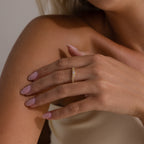 Model wearing a gold pave curve ring with a round center diamond and side pave set stones.
