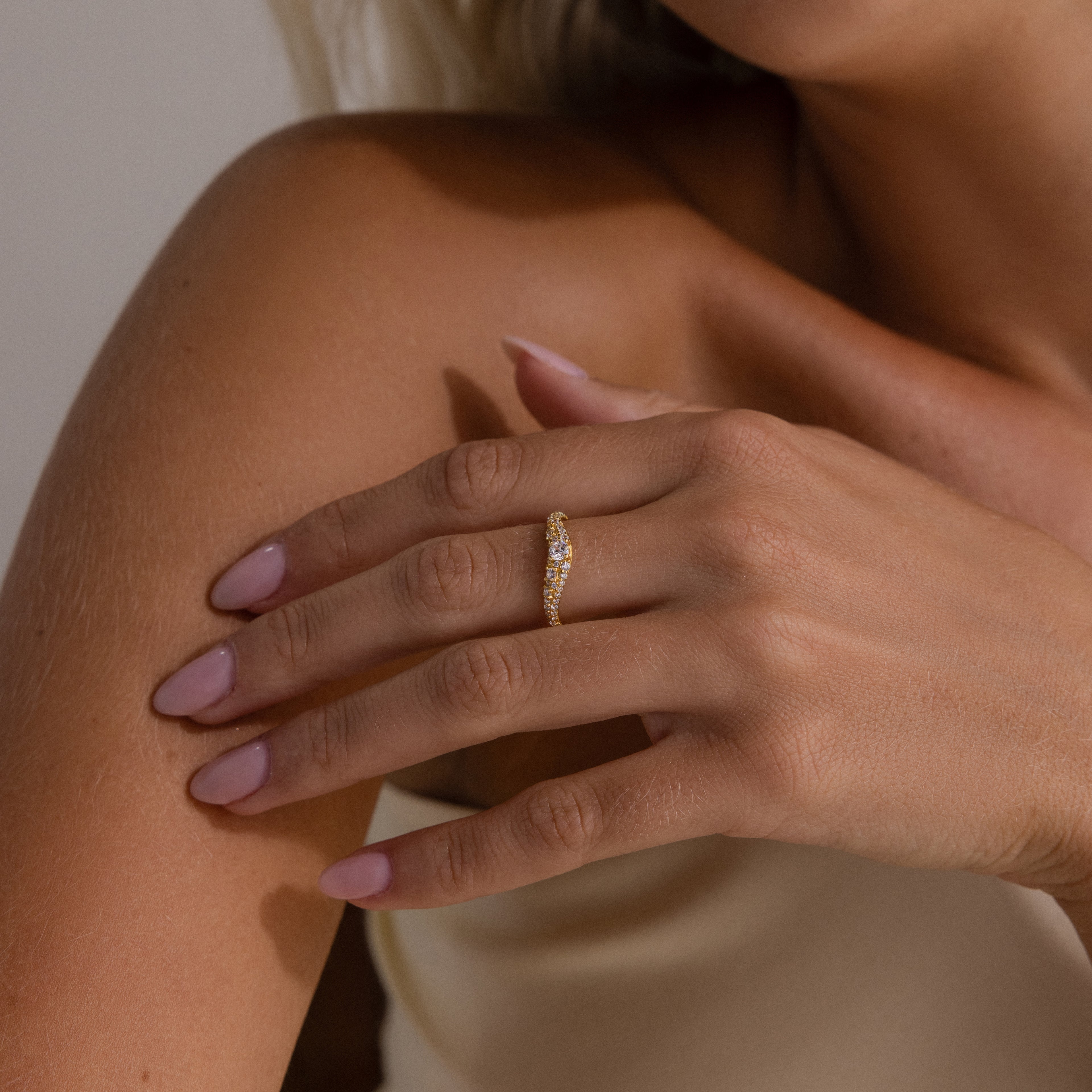 Model wearing a gold pave curve ring with a round center diamond and side pave set stones.