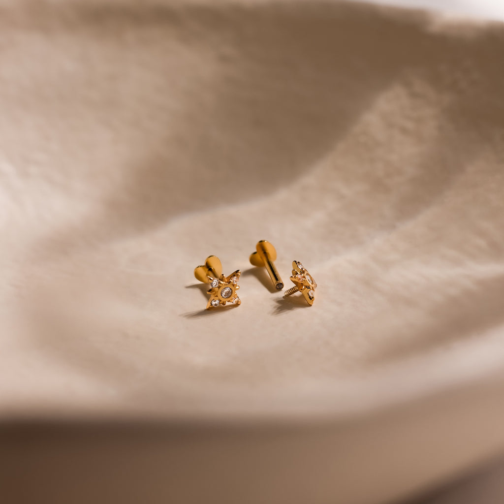 Close up of pair of gold Pave CZ Diamond North Star Studs with heart shaped flat back unscrewed on one earring.