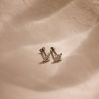 Silver dainty pave cz diamond north star stud earrings with heart shaped flat backings resting against a soft beige background