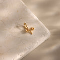 The Zodiac Charm, a gold Aries pendant, rests on a textured beige stone with soft shadows, adding celestial elegance to your jewelry collection.