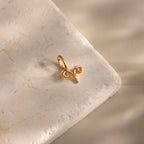 The Zodiac Charm, a gold Aries pendant, rests on a textured beige stone with soft shadows, adding celestial elegance to your jewelry collection.