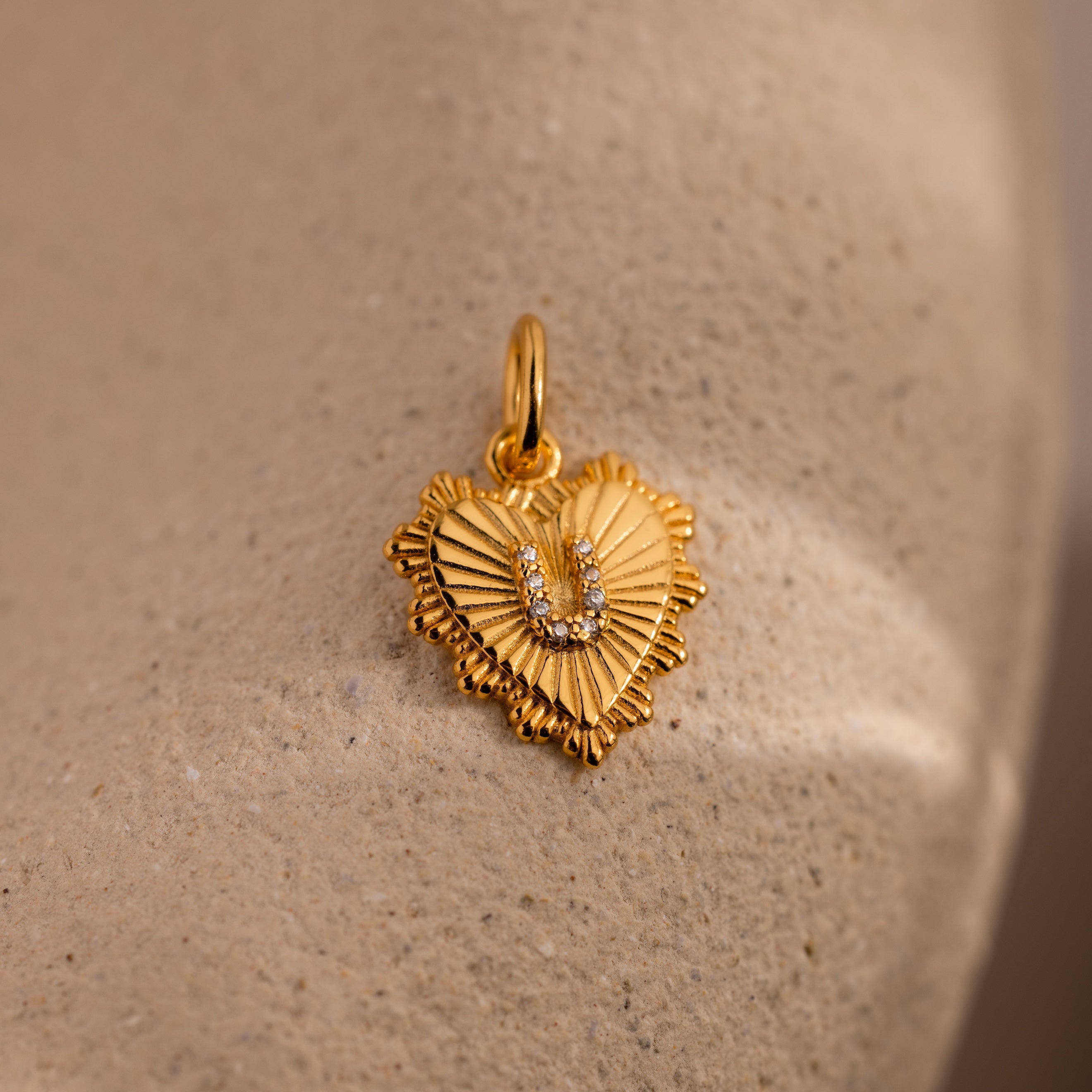 The Ribbed Heart Pave Initial Charm features a textured gold heart design with a diamond-studded letter U, making it an ideal personalized jewelry piece.