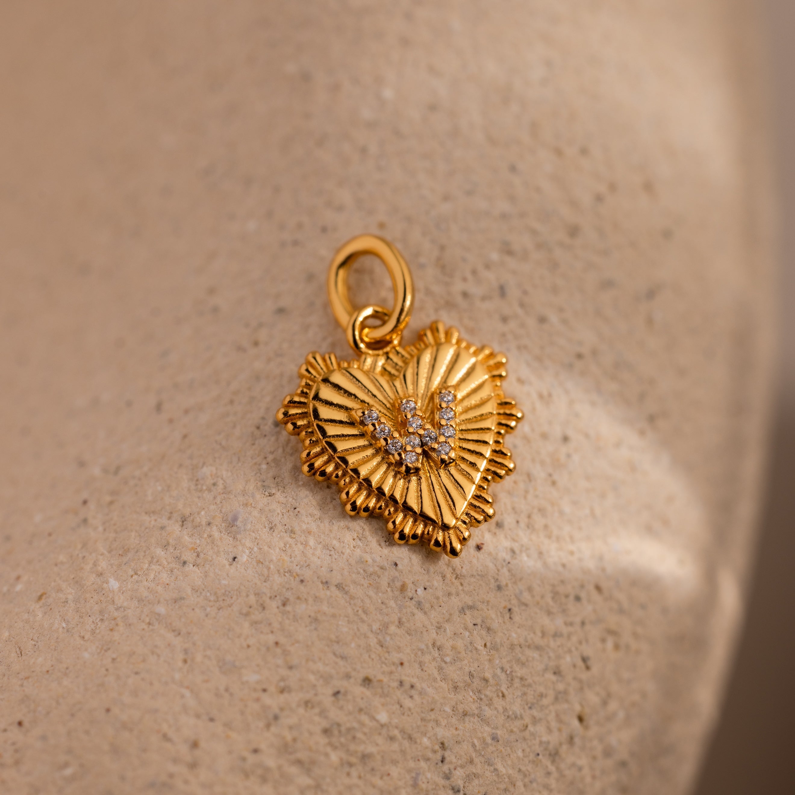 The Ribbed Heart Pave Initial Charm features a textured heart design with sparkling pave accents, ideal for anyone seeking personalized jewelry with timeless elegance.