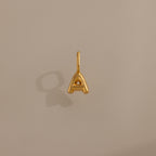 Bubble Letter Charm in 18K Gold shaped as an "A" shown on a plain beige background, casting a subtle shadow to the left.