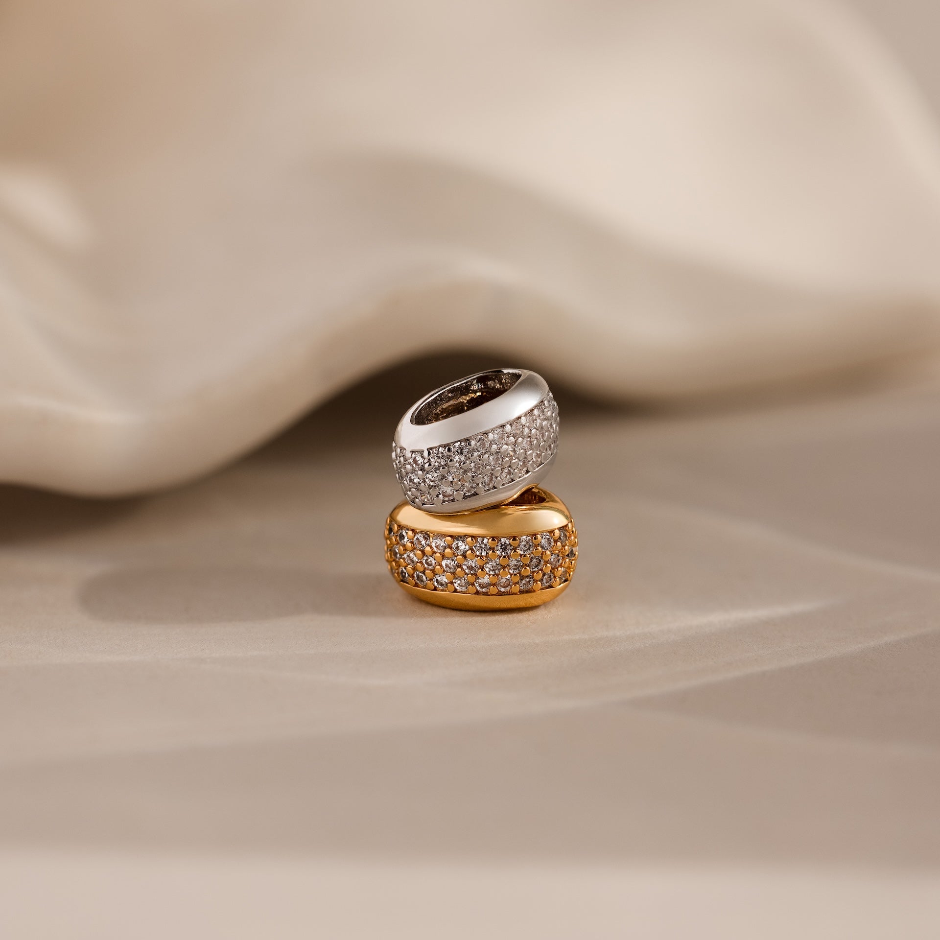 The Bold Pave Dome Charm in Silver, showcased on a soft beige surface, brings a timeless elegance to any jewelry collection.