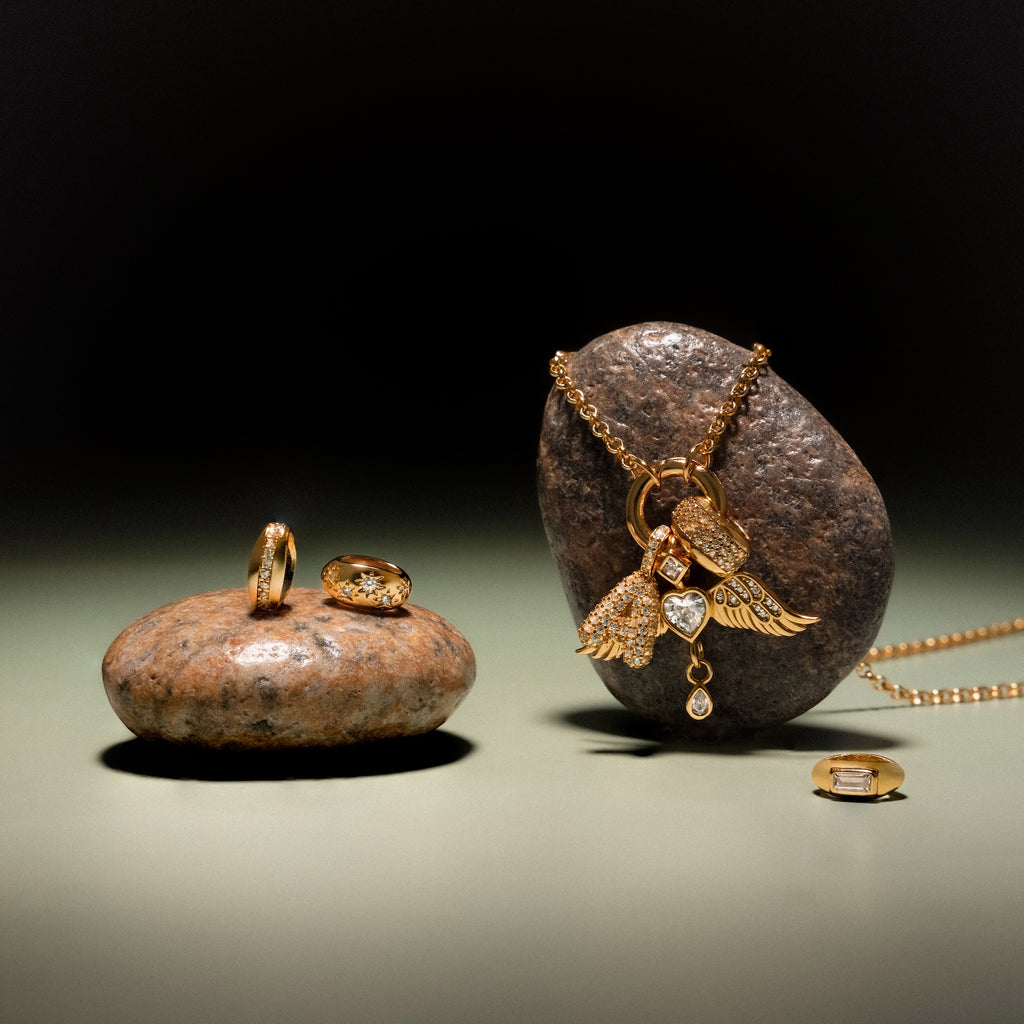 The Bold Pave Dome Charm is displayed on smooth stones against a muted backdrop, creating an elegant jewelry presentation that perfectly highlights its timeless style.