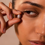 A person holds the Bold Pave Dome Charm in Silver near their eye, their focused expression emphasizing the charm's elegant, delicate design and sparkling silver finish.