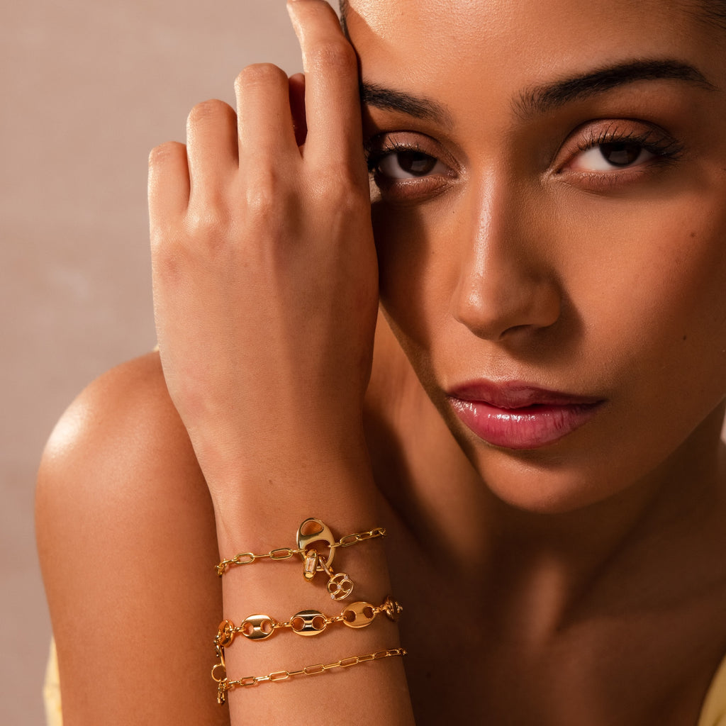 A woman poses gracefully with her hand near her face, drawing attention to the Connector Clasp she wears—an elegant piece that stands out in this exquisite jewelry showcase.
