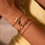 Three Connector Clasp gold chain bracelets with chunky Cuban links shine on a wrist, perfectly paired with a light yellow outfit for a bold, elegant look.