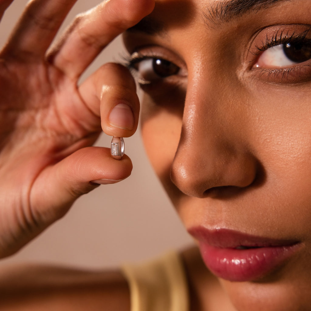 Close-up of a woman holding the Baguette Diamond Charm in Silver near her face, showcasing its detail and brilliance—perfect for highlighting this sparkling silver jewelry piece with diamond accents in SEO-driven product descriptions.