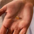 A close-up of a hand holding the Baguette Diamond Charm in the center of the palm.