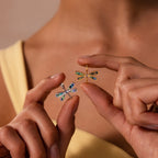 A person holds two Abalone Dragonfly Charms in Silver, each featuring nature-inspired design and iridescent wings.