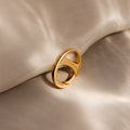 A Connector Clasp in gold with a modern design rests on soft, beige fabric under gentle, diffused lighting.