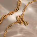 The Connector Clasp gold chain necklaces, featuring unique links and displayed on soft, light fabric, are statement pieces that elevate any outfit with timeless elegance.
