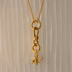 The Knot Charm Clasp in 18K Gold features interlocking links and a dangling letter A charm accented with a clear gemstone—an elegant, personalized jewelry piece ideal for gifts or everyday wear.