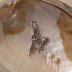 Knot Charm Clasp in Silver: Elegant keychain featuring fish, starfish, and seashell charms, artfully displayed on an iridescent oyster shell with two pearls. Perfect ocean-inspired accessory for any occasion.