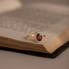 The Pave Garnet Ring, inspired by January’s birthstone and framed with sparkling diamonds, rests on the open pages of an old book.