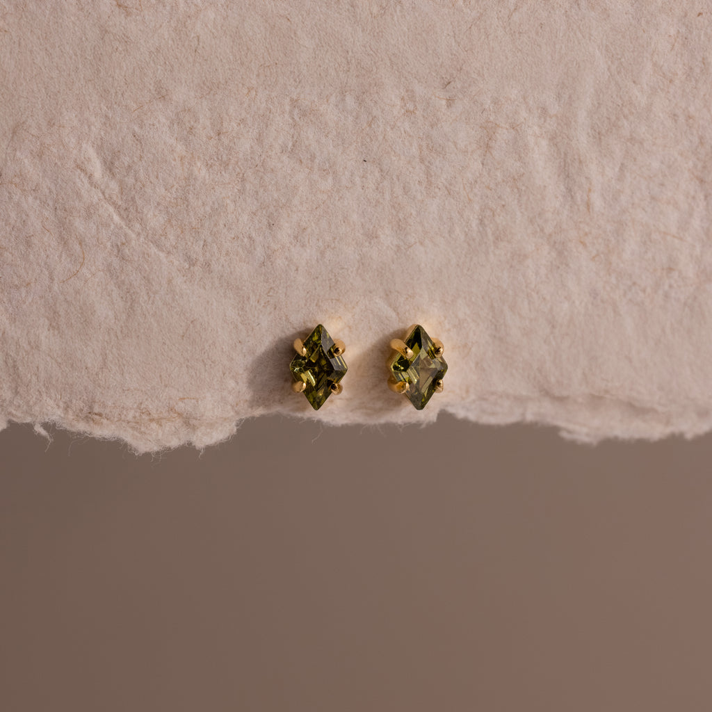 Rhombus Peridot Flatback Studs with gold settings shown on a textured off-white surface—ideal for adding a pop of modern green glamour.