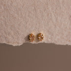 Rhombus Topaz Flatback Studs—small earrings blending gold and diamond accents with modern glamour, shown on a textured beige background.