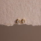 Rhombus Diamond Flatback Studs and other gold and diamond earrings are displayed on textured beige paper, creating an understated chic jewelry look.
