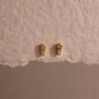 Tiny Duo Topaz Flatback Studs with a delicate diamond accent, displayed on a textured beige paper background.