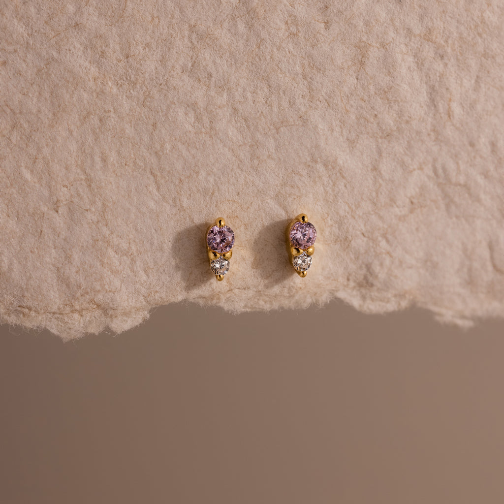 Tiny Duo Alexandrite Flatback Studs featuring purple birthstones and diamond accents, displayed on textured beige paper—perfect for your ear stack.