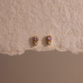Tiny Duo Pink Tourmaline Flatback Studs featuring pink tourmaline stones and diamond accents, displayed on a textured beige surface.