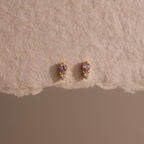 Tiny Duo Pink Tourmaline Flatback Studs featuring pink tourmaline stones and diamond accents, displayed on a textured beige surface.