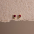 Tiny Duo Ruby Flatback Studs featuring small red and clear stones, displayed on textured beige paper.