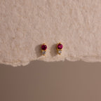 Tiny Duo Ruby Flatback Studs featuring small red and clear stones, displayed on textured beige paper.