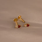 The Tiny Duo Birthstone Flatback Studs, crafted in gold with red and clear gemstones, bring elegance to any look. These dazzling birthstone studs beautifully enhance even the most neutral styles.