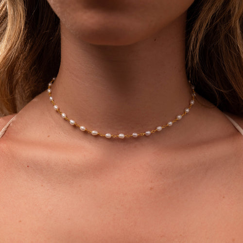 Aurora Pearl Station Necklace: Gold chain with luminous freshwater pearls on a woman's neck.