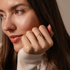 A woman with long brown hair rests her chin on her hand, wearing a romantic jewelry piece—the Toi et Moi Wrap Ring in Silver.