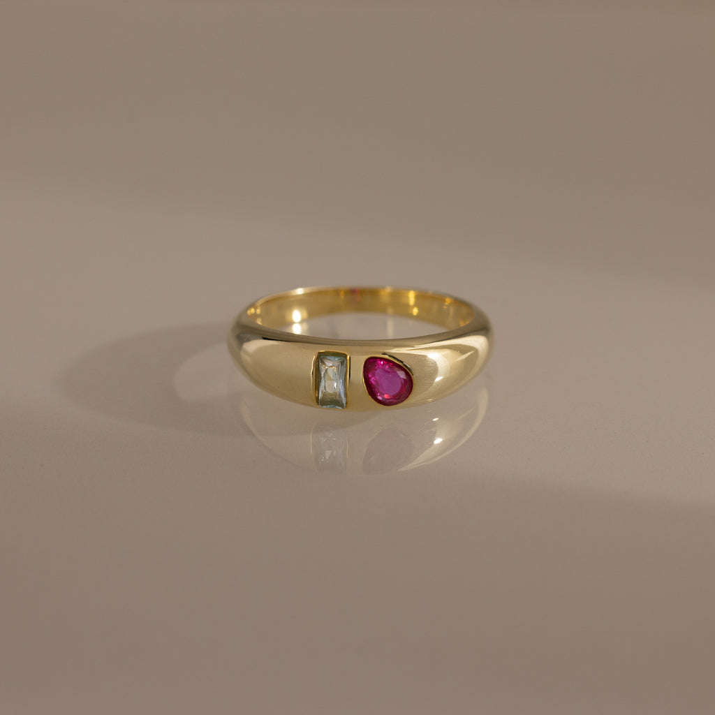The Toi et Moi Dome Ring in 18K Gold features a rectangular clear stone and an oval pink stone set side by side on a smooth band.